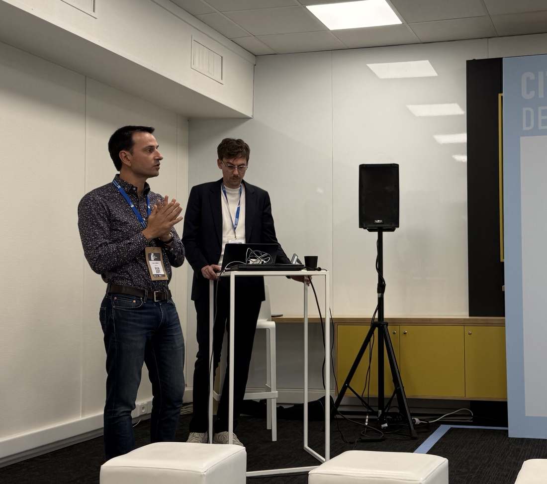 Deux intervenants présentant le pitch d'Atecna sur la scène de la Cité de l'IA, devant le fond Tech & Business Day du 15 juin 2026