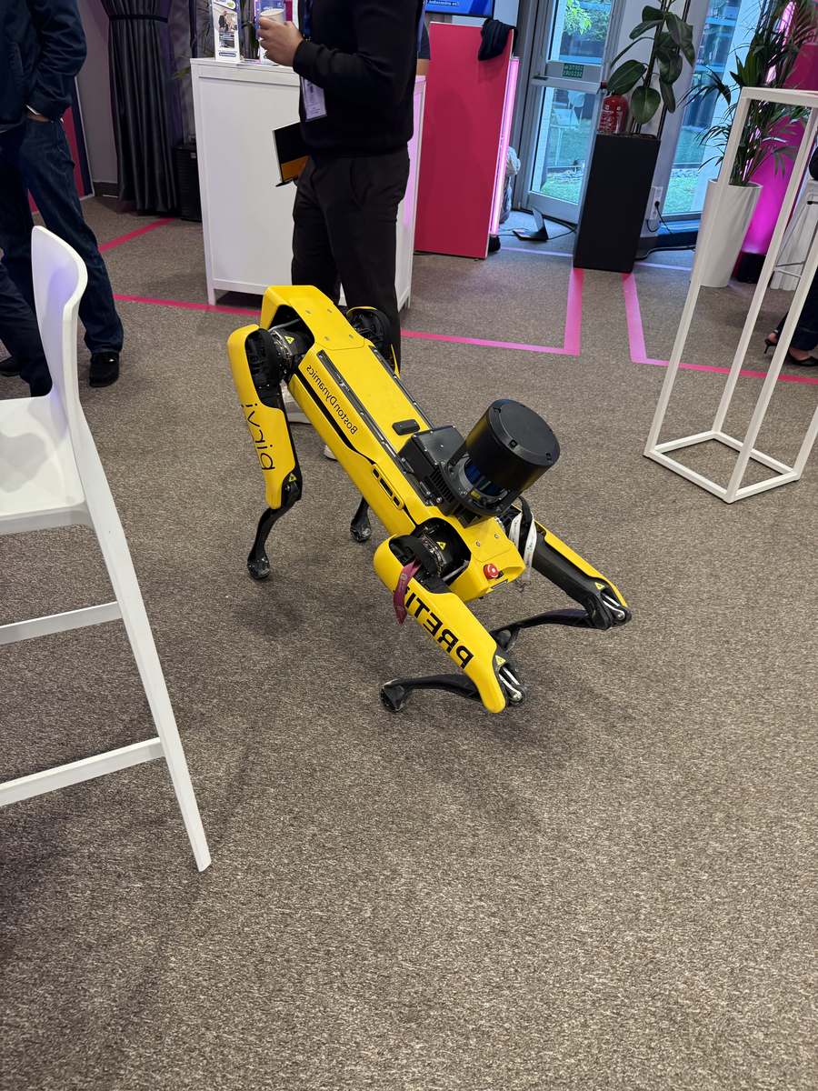 Robot quadrupède Boston Dynamics Spot, jaune, lidar sur le dos, en démonstration dans les allées de la Cité de l'IA